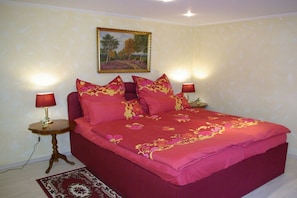 A bedroom with a large bed, two bedside tables, and a painting on the wall. - Holiday apartment with 1 bedroom (Himmelpfort)