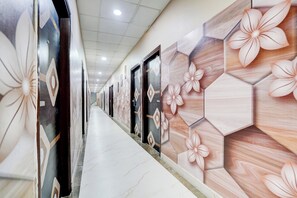 Un couloir aux murs et aux portes décorés de motifs, qui mène à un escalier.