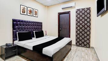 A bedroom with a bed, bedside table, and a TV mounted on the wall.
