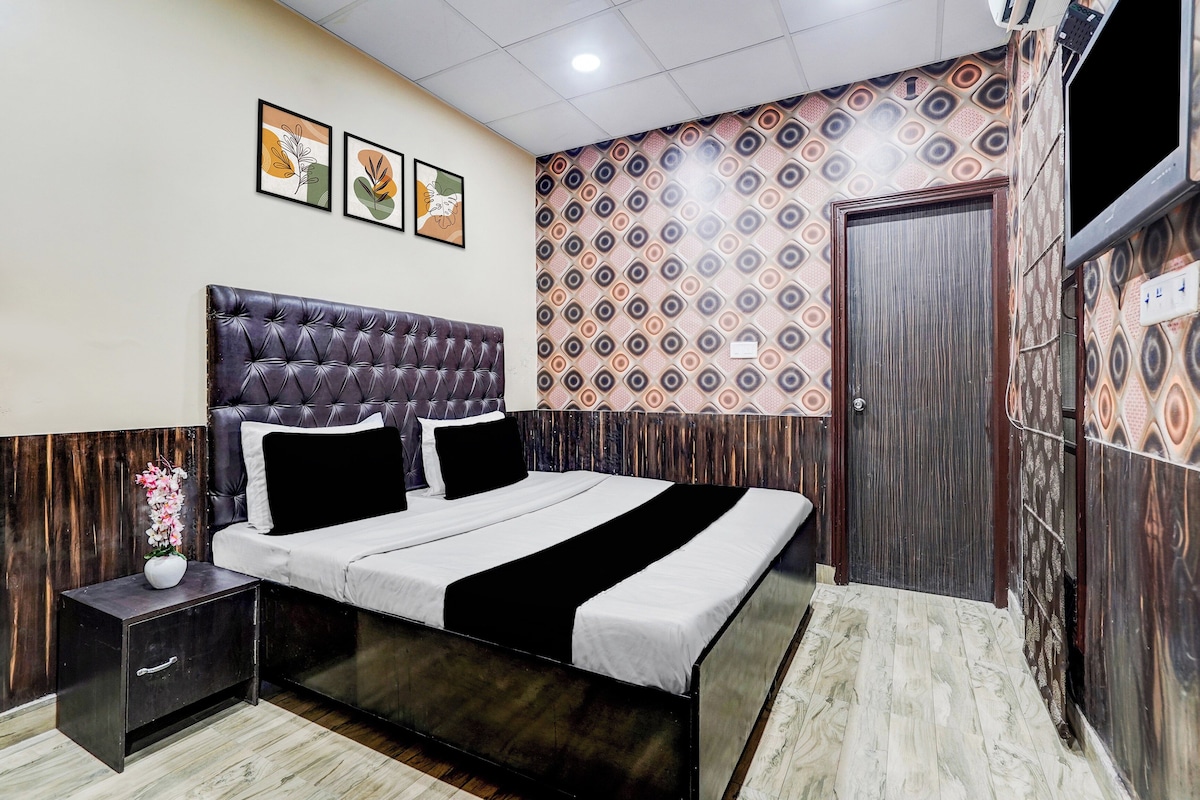 Un dormitorio con cama, mesitas de noche, televisor montado en la pared y un papel tapiz estampado.