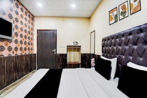 Una habitación de hotel con una cama, televisión, espejo y puerta.