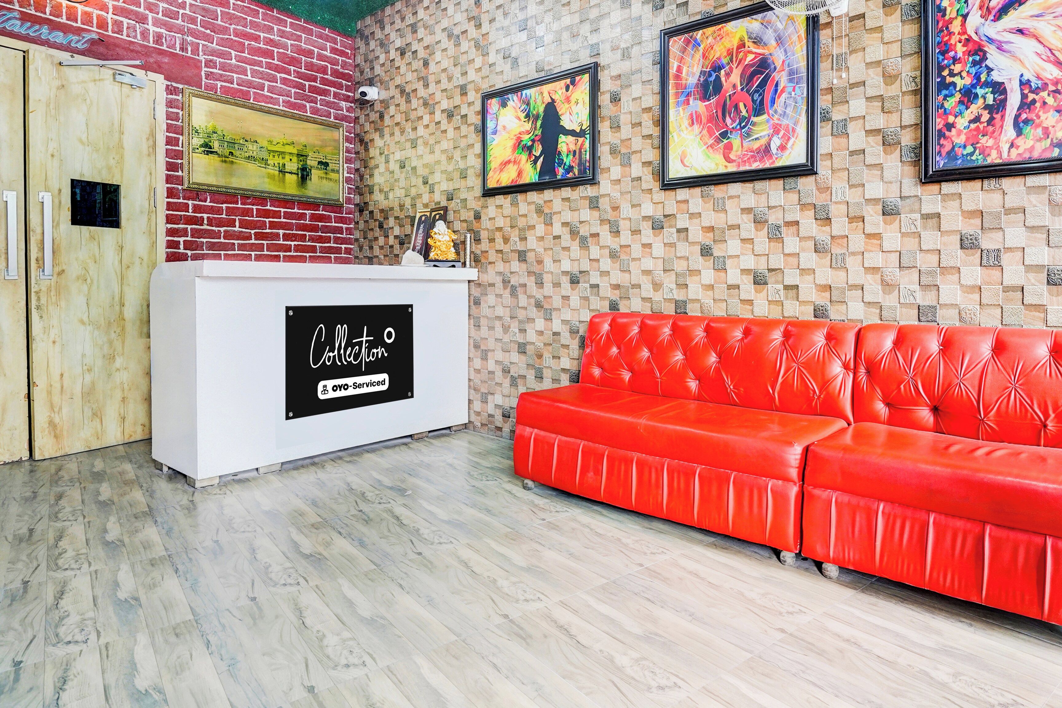 A reception area with a white counter, red leather sofa, and a brick wall with artwork.