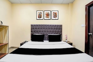 Habitación de hotel con una cama grande, un escritorio de madera, un teléfono y tres obras de arte enmarcadas en la pared.