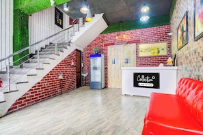 Un interior moderno con una escalera, un mostrador de recepción y un sofá rojo.