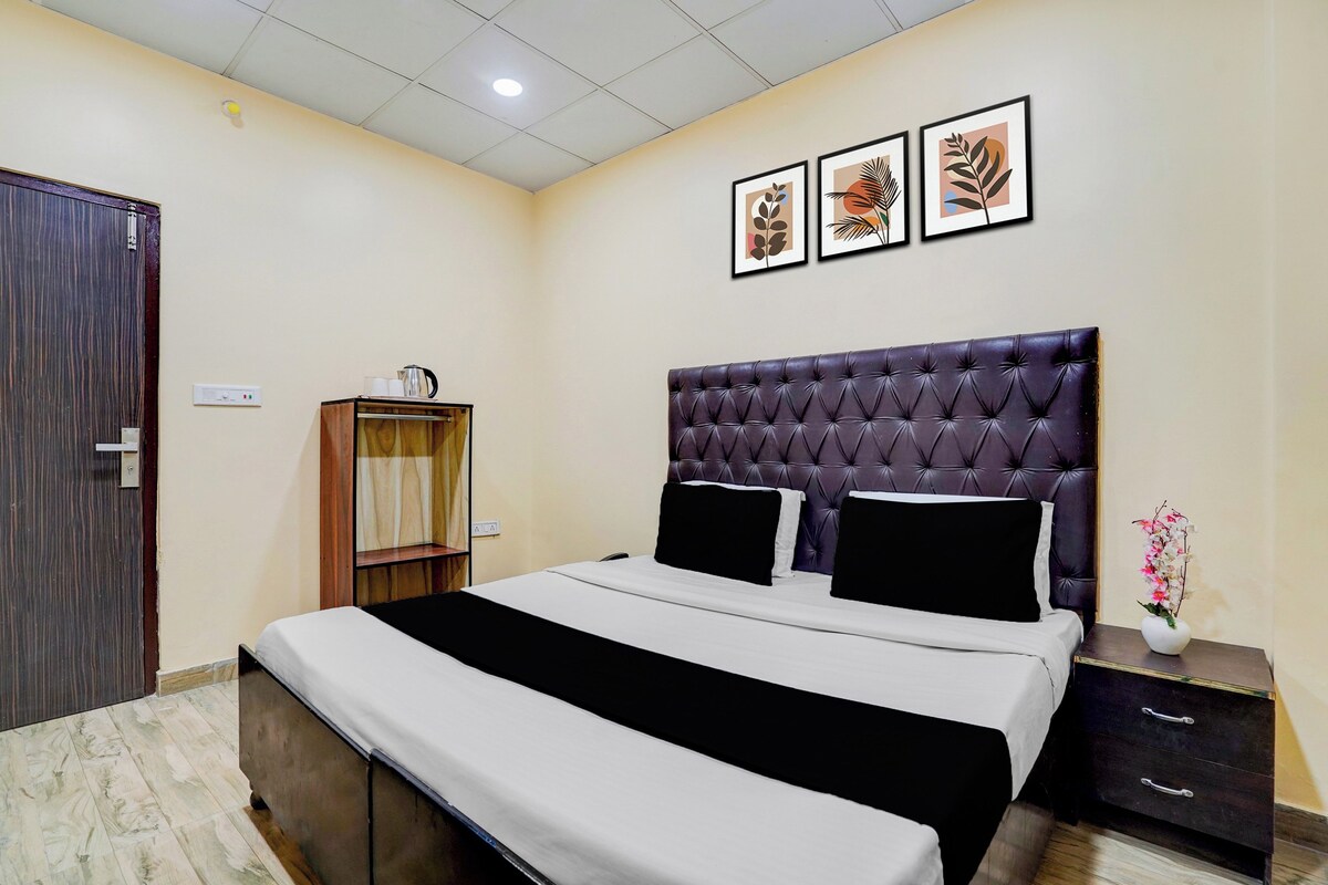 Habitación de hotel con una cama grande, una mesita de noche, un armario y una pared con tres cuadros enmarcados.