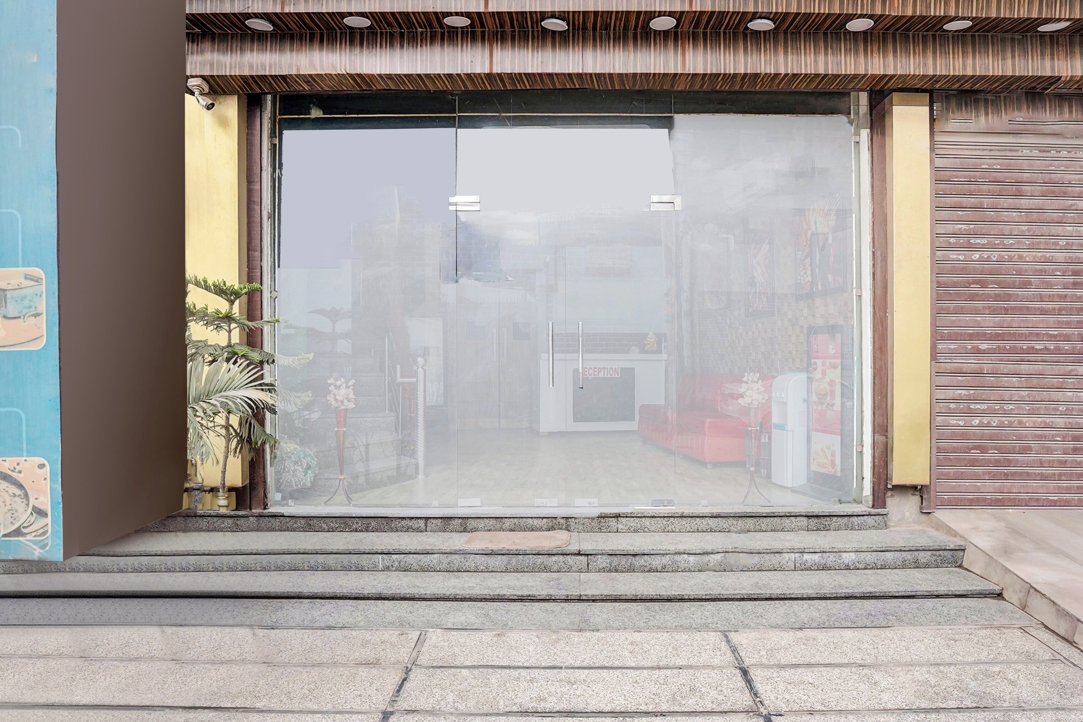 A storefront with a clear glass entrance, a reception desk, and a closed shutter on the right.