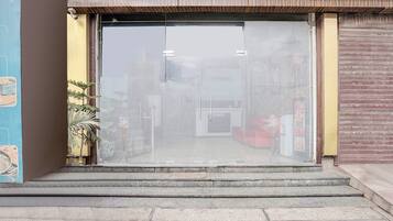 A storefront with a clear glass entrance, a reception desk, and a closed shutter on the right.