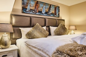 A hotel room with a large bed, two nightstands, a painting of sailboats, and a fur throw on the bed. - Holiday apartment with 1 bedroom (Rantum)