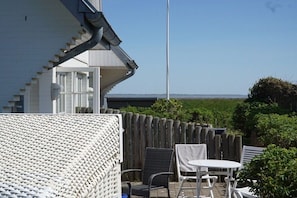 A patio with a white wicker sofa, two chairs, and a small table. - Holiday apartment with 1 bedroom (Rantum)