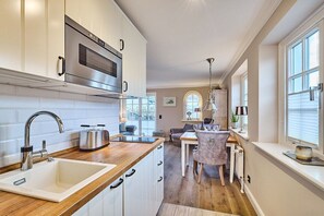 A modern kitchen with a built-in oven, a sink, and a dining area with a table and chairs. - Holiday apartment with 1 bedroom (Rantum)