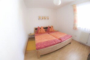 A bedroom with a double bed, a bedside table, a wall-mounted light fixture, and a window with a curtain. - Holiday apartment with 2 bedrooms (Millstatt)