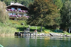A lakeside property with a multi-story building, a dock, and a kayak. - Holiday apartment with 2 bedrooms (Millstatt)
