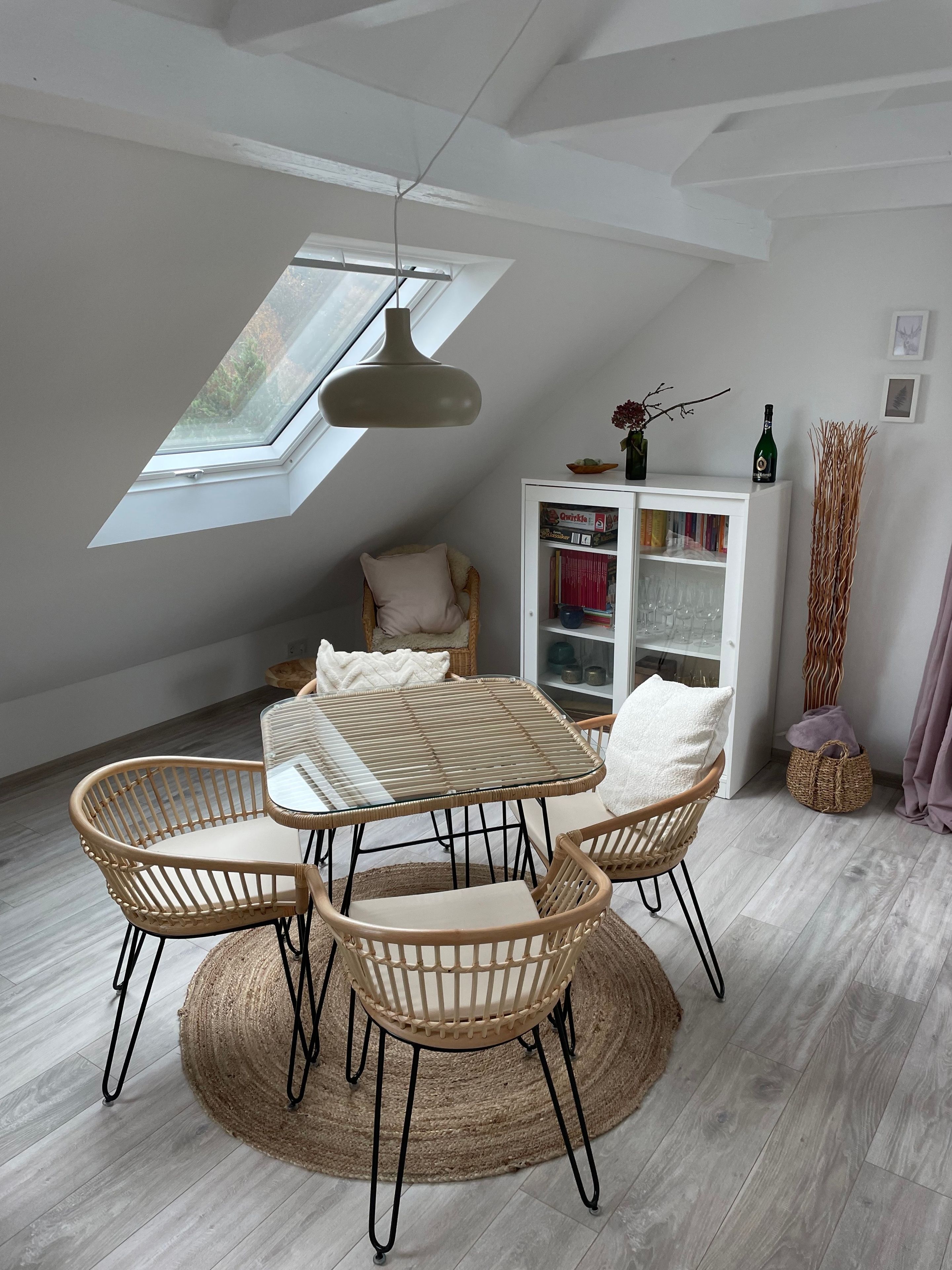 Un coin repas avec une table et des chaises, une bibliothèque et une fenêtre avec un puits de lumière.