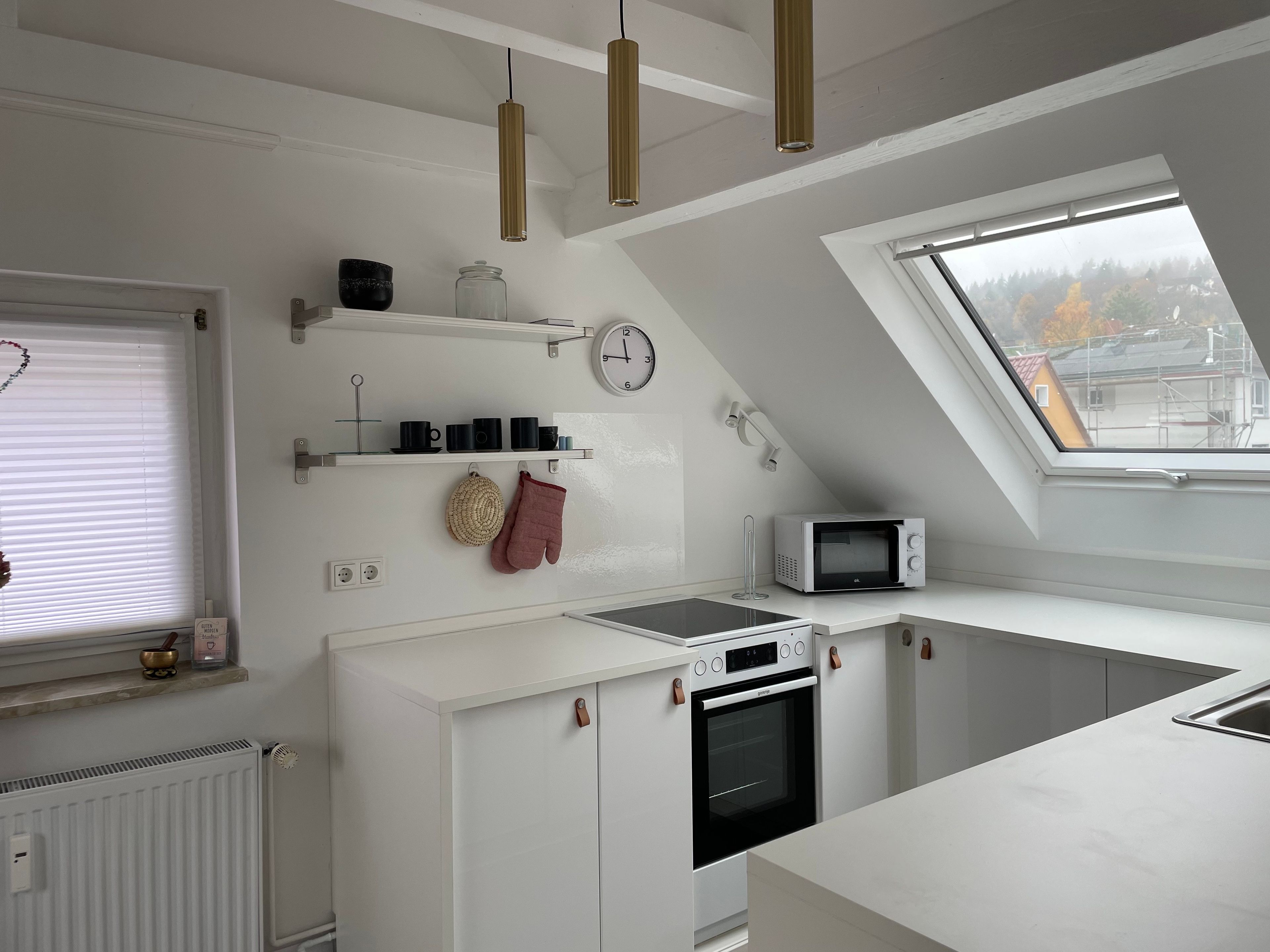 Eine moderne Küche mit weißen Schr änken, einer Mikrowelle, einem Backofen und einem Oberlicht.