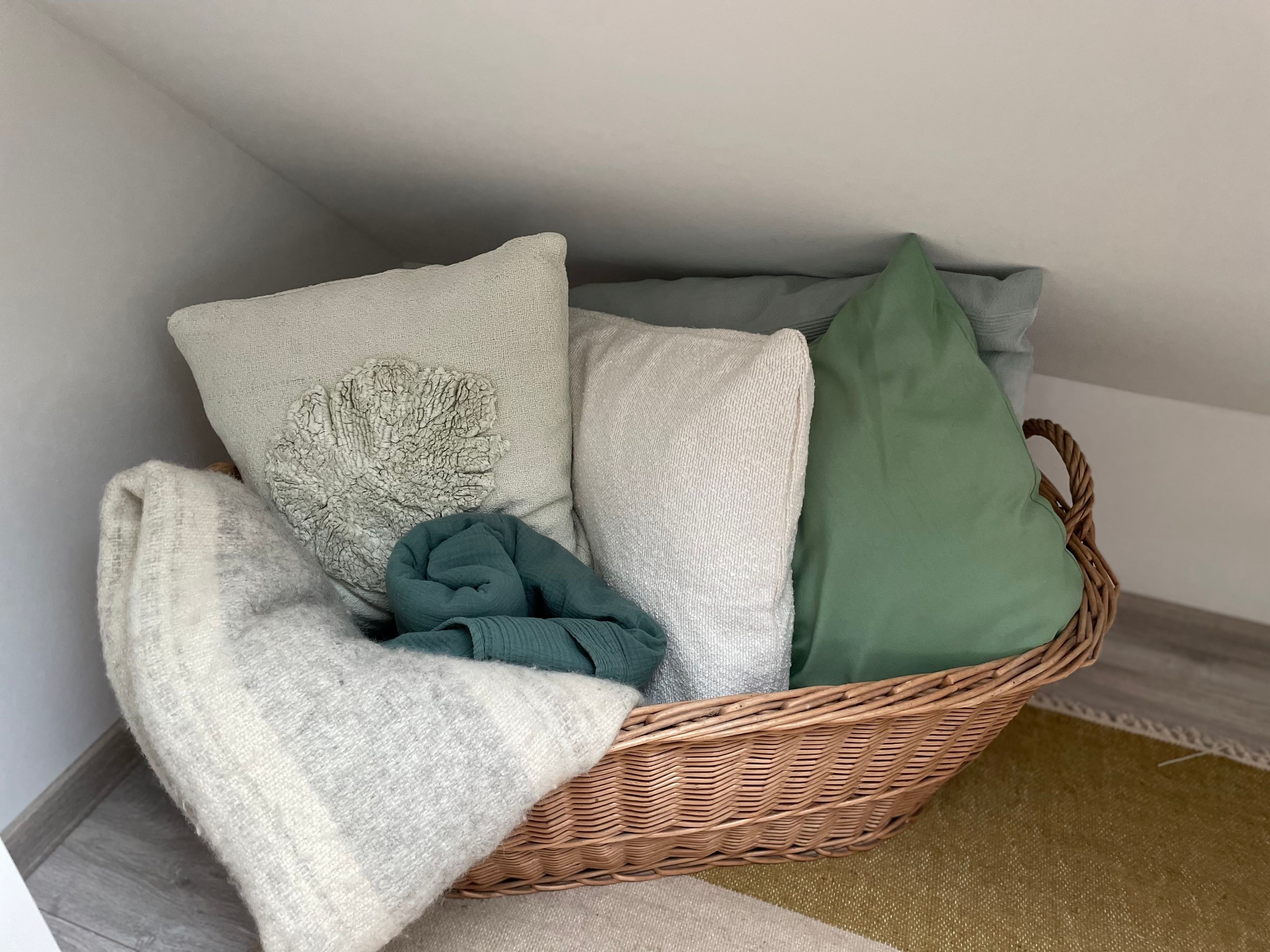 A wicker basket with pillows and a blanket.