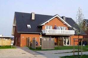 A two-story residential building with a balcony, a garage, and a small garden area. - Holiday apartment with 2 bedrooms (Burg auf Fehmarn)