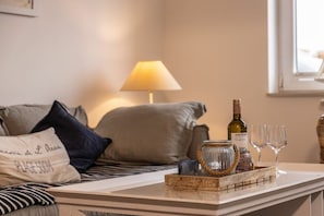 A neatly arranged living area with a sofa, pillows, a table with a tray of items, a lamp, and a bottle. - 50111 Fisherman's Loft (Carolinensiel)