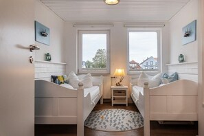 A room with two beds, a small table, and a window. - 50111 Fisherman's Loft (Carolinensiel)