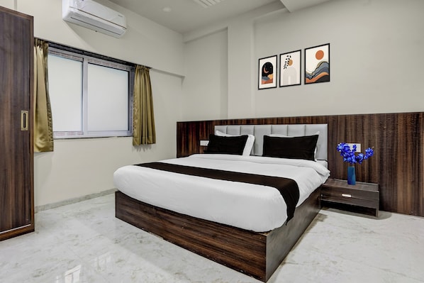 A modern hotel room with a large bed, a nightstand, a vase of flowers, and artwork on the wall.