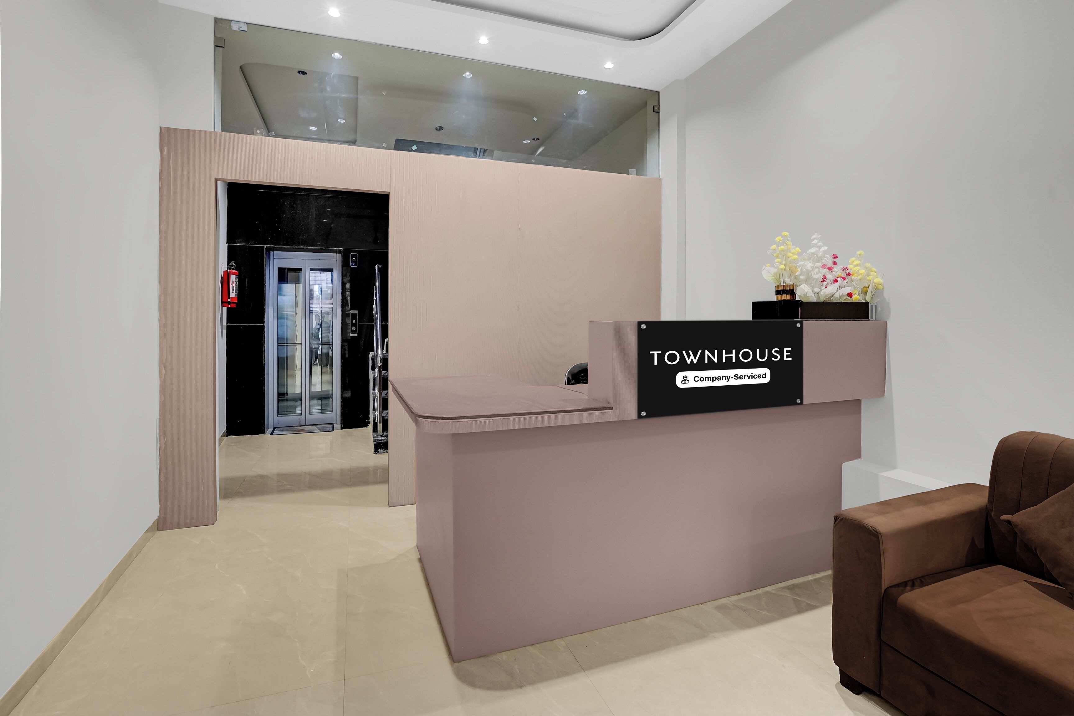 A reception desk with a sign that reads 'TOWNHOUSE Company-Serviced' and a flower arrangement on top.