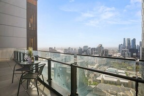 A balcony with a glass railing overlooking a cityscape. - Southbank Balcony 3 Bedroom (Southbank)