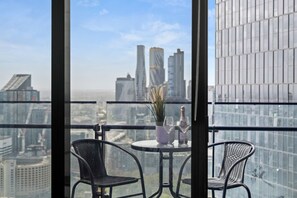 A balcony with two chairs and a table, a potted plant, and a bottle of champagne. - Southbank Balcony 3 Bedroom (Southbank)