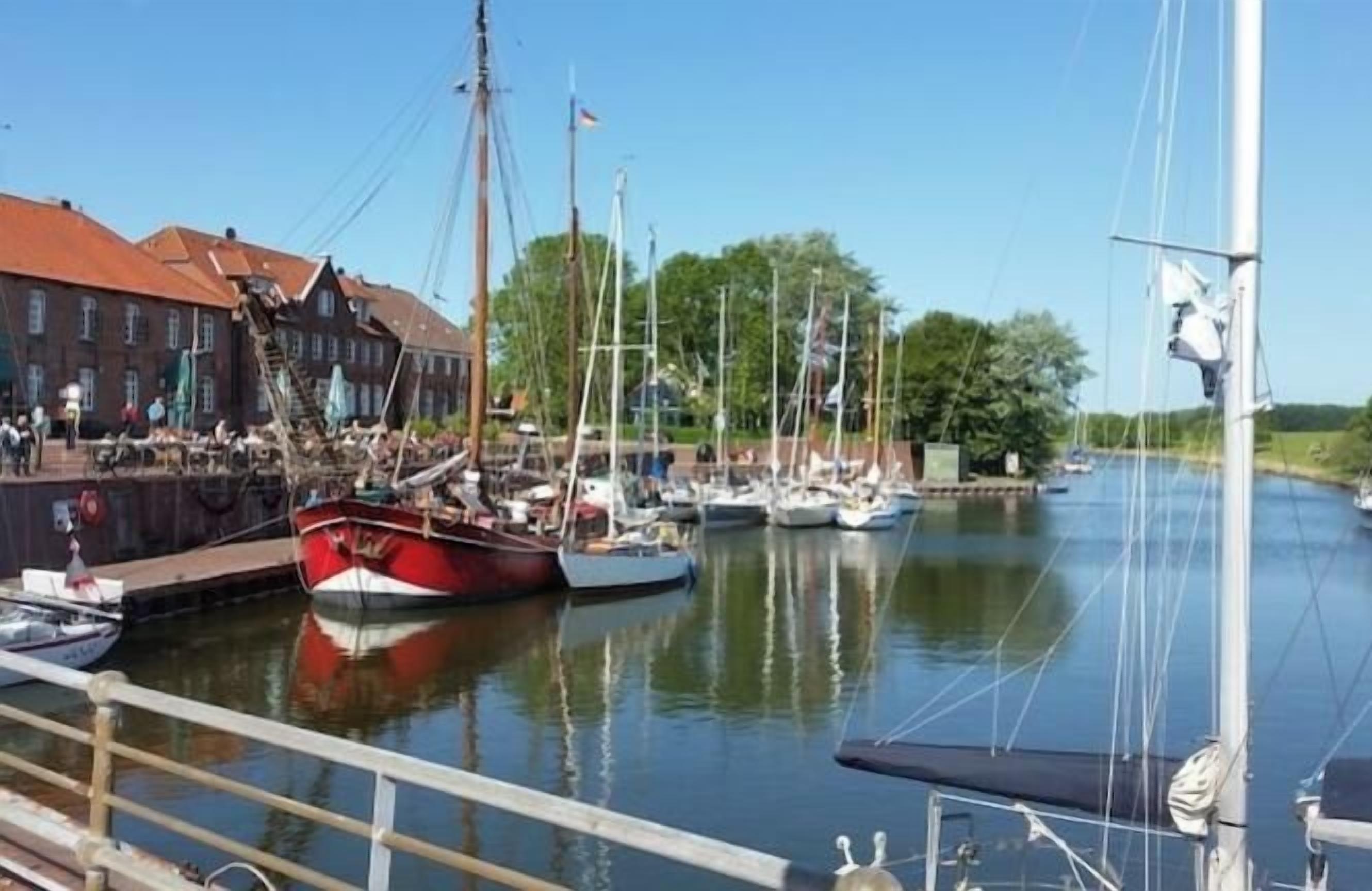 A marina with boats docked, a building with a red roof, and a clear sky.