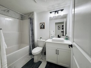 A bathroom with a shower, toilet, sink, and mirror. - Premium, Family-friendly 2-bedroom Private Suite (Calgary)