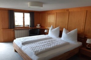 Ein Zimmer mit Holzwänden, einem Bett, einem Schreibtisch und einem Fenster.