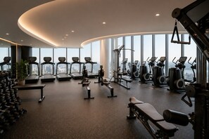 A modern gym with treadmills, elliptical machines, and free weights. - Sky High 3 Bedroom City Stay (Melbourne)