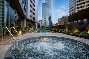Un hôtel moderne doté d’une piscine, d’un jacuzzi et offrant une vue sur les immeubles environnants.