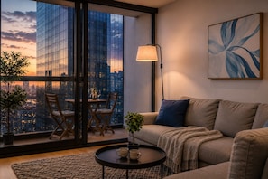 Uma sala de estar moderna com um sofá, uma mesa de jantar com cadeiras, um abajur e uma janela grande com vista para a cidade.