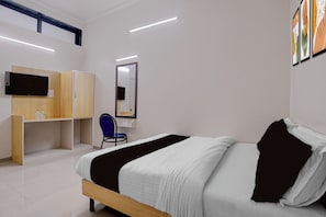 A hotel room with a bed, a desk, a chair, a wardrobe, a mirror, and a television.