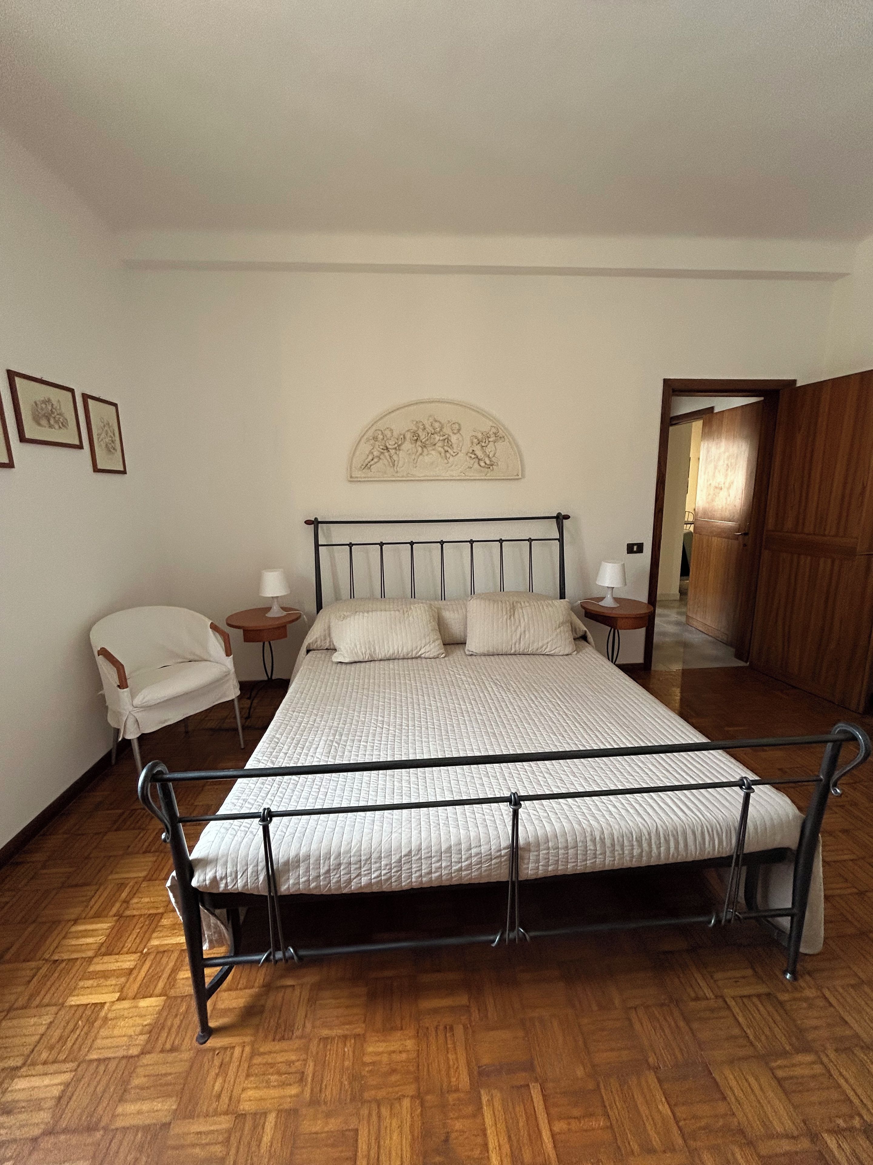Une chambre à coucher avec un lit, une chaise, une table de chevet et une porte.
