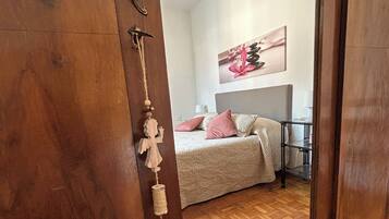 Een slaapkamer met een bed, nachtkastje, lamp en een aan de muur hangend schilderij.