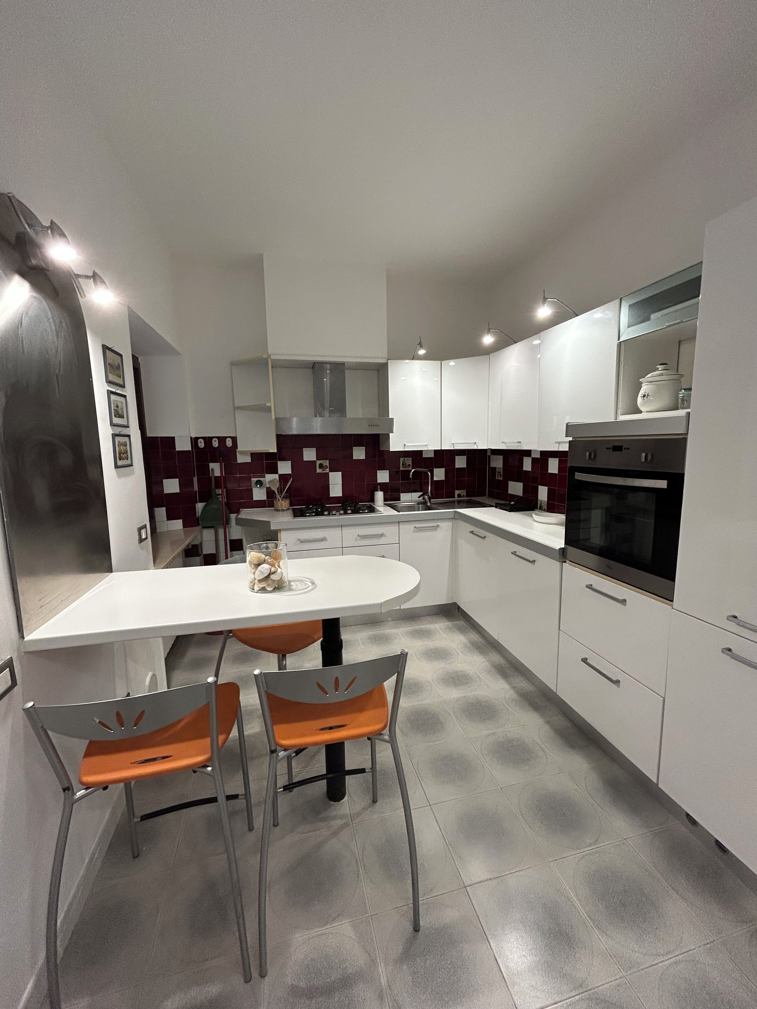 Una cocina moderna con encimera blanca, electrodomésticos de acero inoxidable y salpicadero de azulejos.