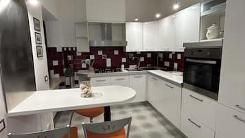Una cocina moderna con encimera blanca, electrodomésticos de acero inoxidable y salpicadero de azulejos.