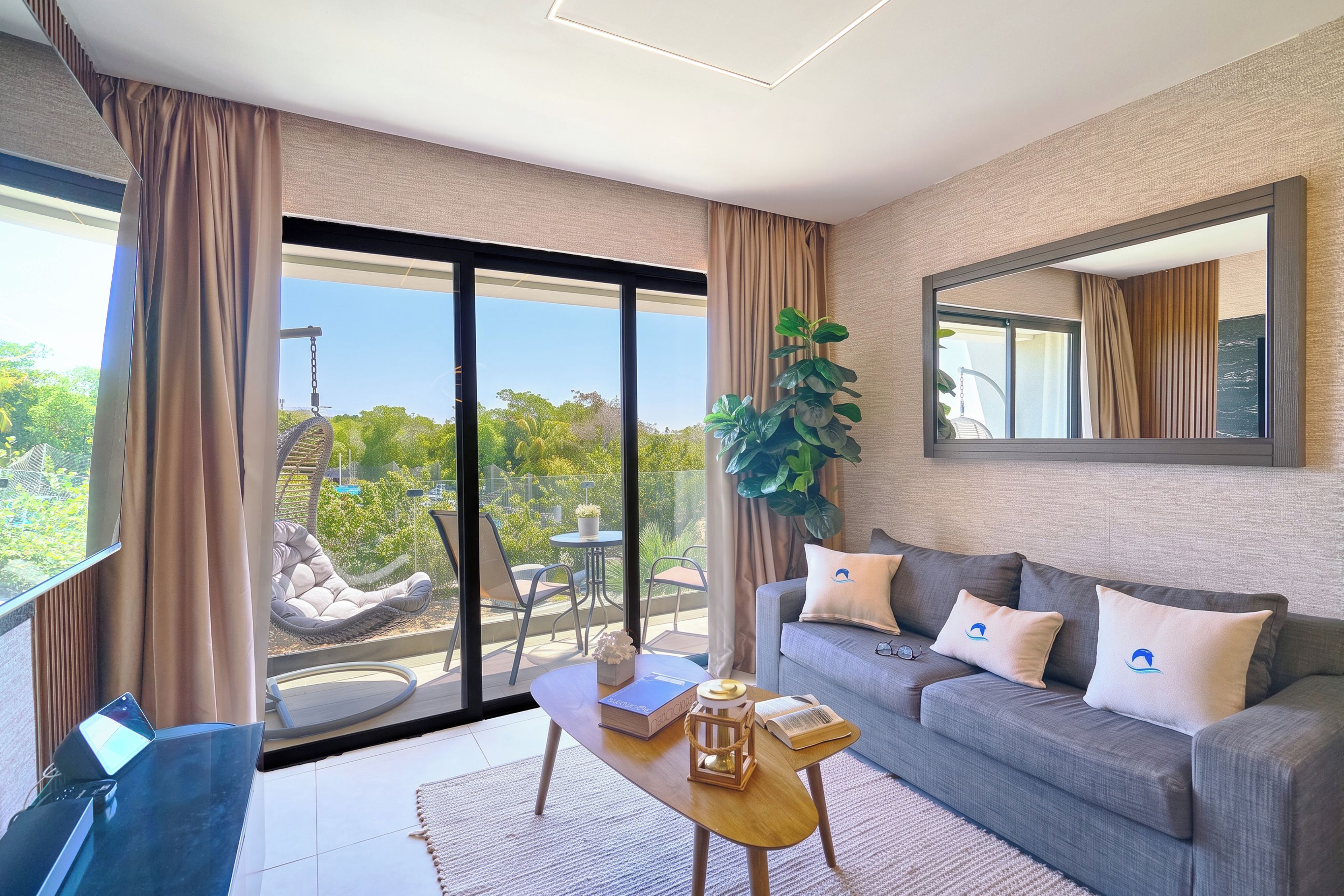 A modern living room with a sofa, coffee table, and a large window with a view of greenery.