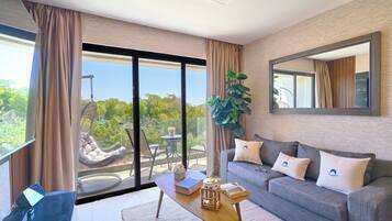 A modern living room with a sofa, coffee table, and a large window with a view of greenery.