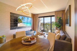 A modern dining area with a wooden table, chairs, and a view of the outdoors. - Modern 2-bedroom, 2-bathroom condo inside gated Cap Cana. Room for the whole family, or a private bedroom for each couple. Minutes from Juanillo Beach and El Dorado Water Park, 10 min from the airport. (Punta Cana)