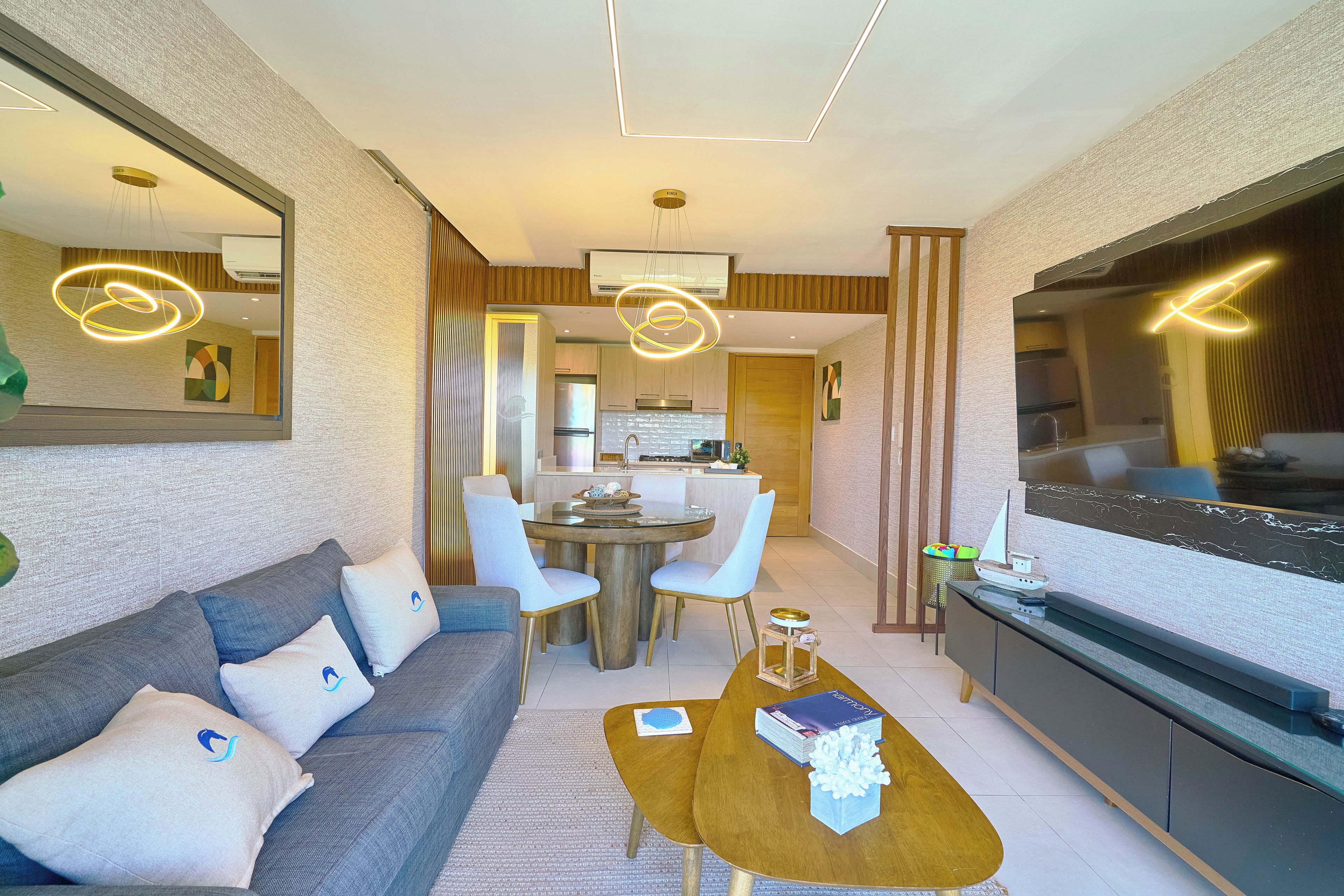 A modern living room with a sofa, coffee table, and a dining area with chairs.