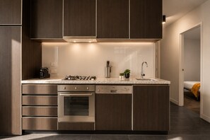 A modern kitchen with built-in appliances, a countertop, and a sink. - Stadium Side 2 Bedroom Retreat (Docklands)