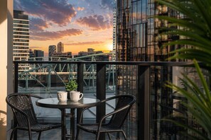 A balcony with two wicker chairs, a small round table, and two white mugs. - Stadium Side 2 Bedroom Retreat (Docklands)