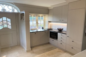 A kitchen with white cabinetry, a black countertop, and a window with a view of greenery. - Holiday home in Kampen with swimming pool (Kampen)