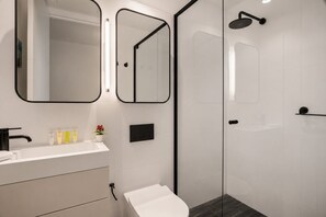 Ein modernes Badezimmer mit einem weißen Waschbecken, Spiegel und Dusche.
