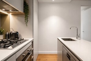 A modern kitchen with a gas stove, a coffee machine, a sink, and a dishwasher. - 70th Floor City View Apartment (Melbourne)