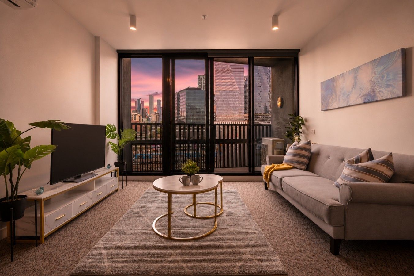 A modern living room with a flat-screen TV, a sofa, a coffee table, and a large window with a city view.