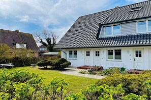 A residential house with a sloped roof, a front porch, and a well-maintained lawn. - Holiday apartment with 2 bedrooms (Wenningstedt)