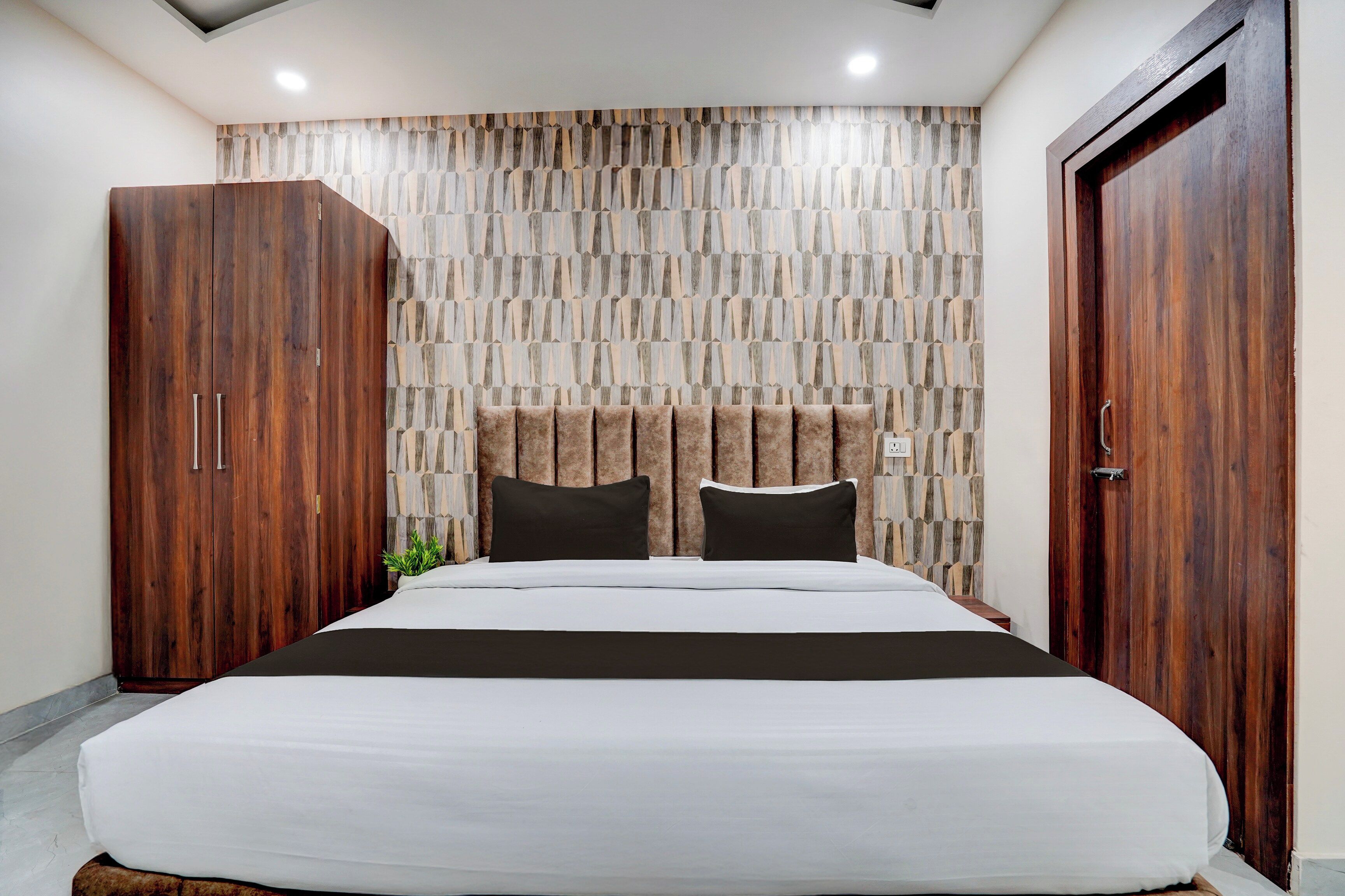 Un dormitorio con una cama grande, un armario de madera y una pared con estampado.