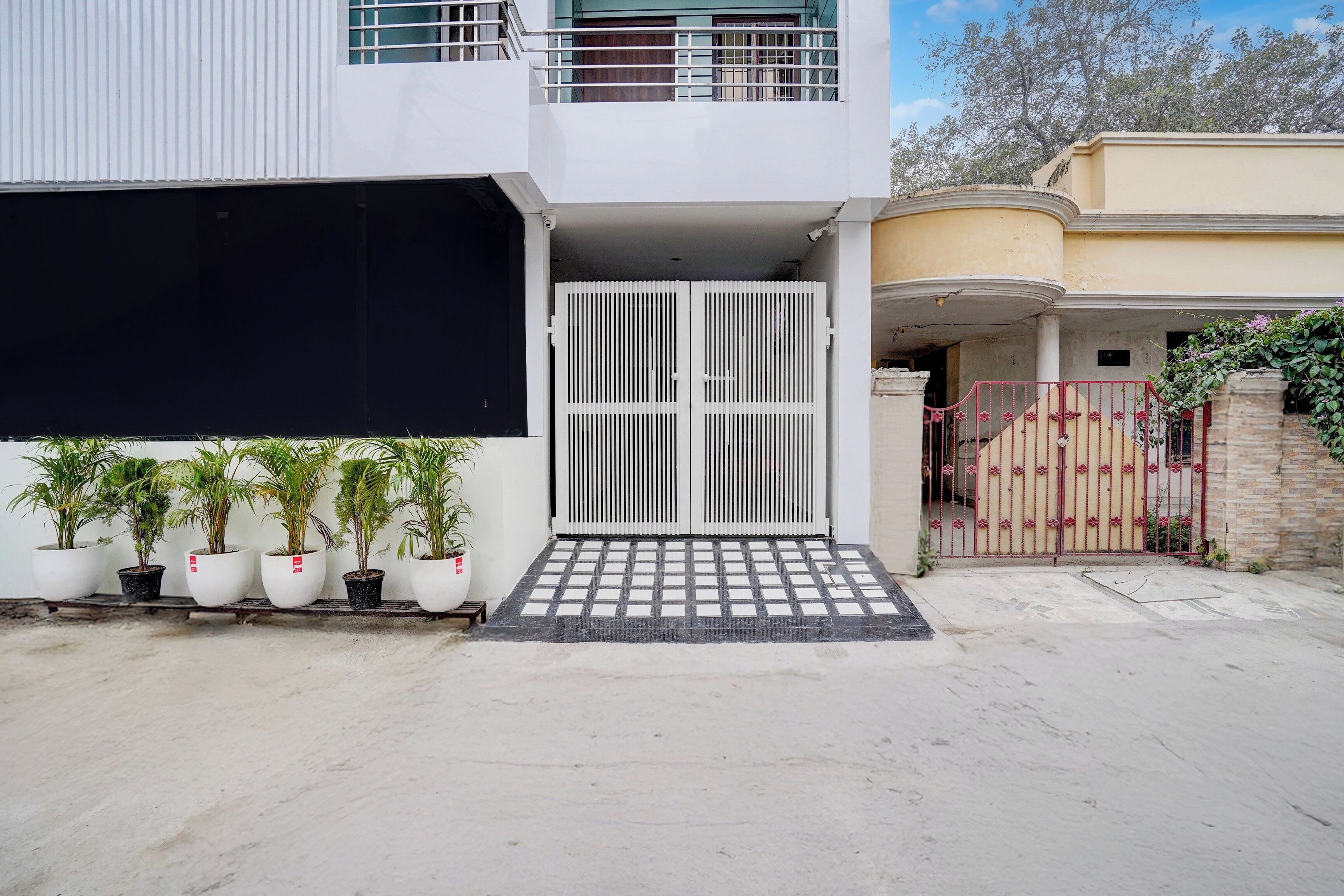 Un edificio moderno con entrada protegida, plantas en macetas y cielo despejado.